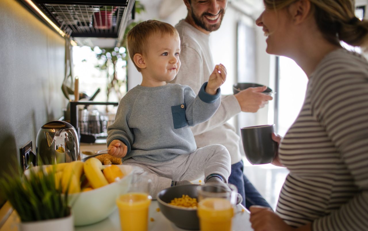Kleinkind isst mit Familie in der Küche