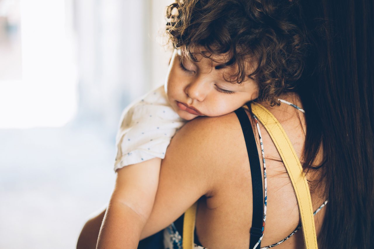 Kleinkind schläft auf der Schulter der Mutter